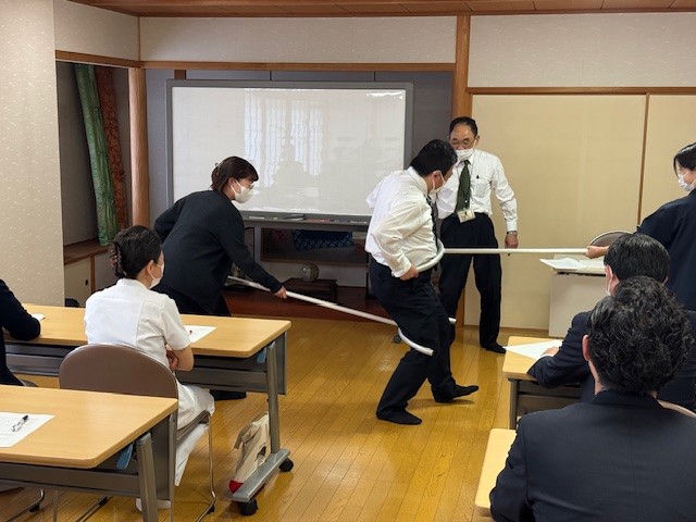 職員がさすまたを使用し、制圧技術を実践。 2人の職員がさすまたを持ち、正しい操作方法を確認しながら演習を行っています。